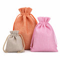 Three small drawstring pouches in different colors: a large peach-orange one, a medium pink one, and a small light beige one, arranged against a plain white background.
