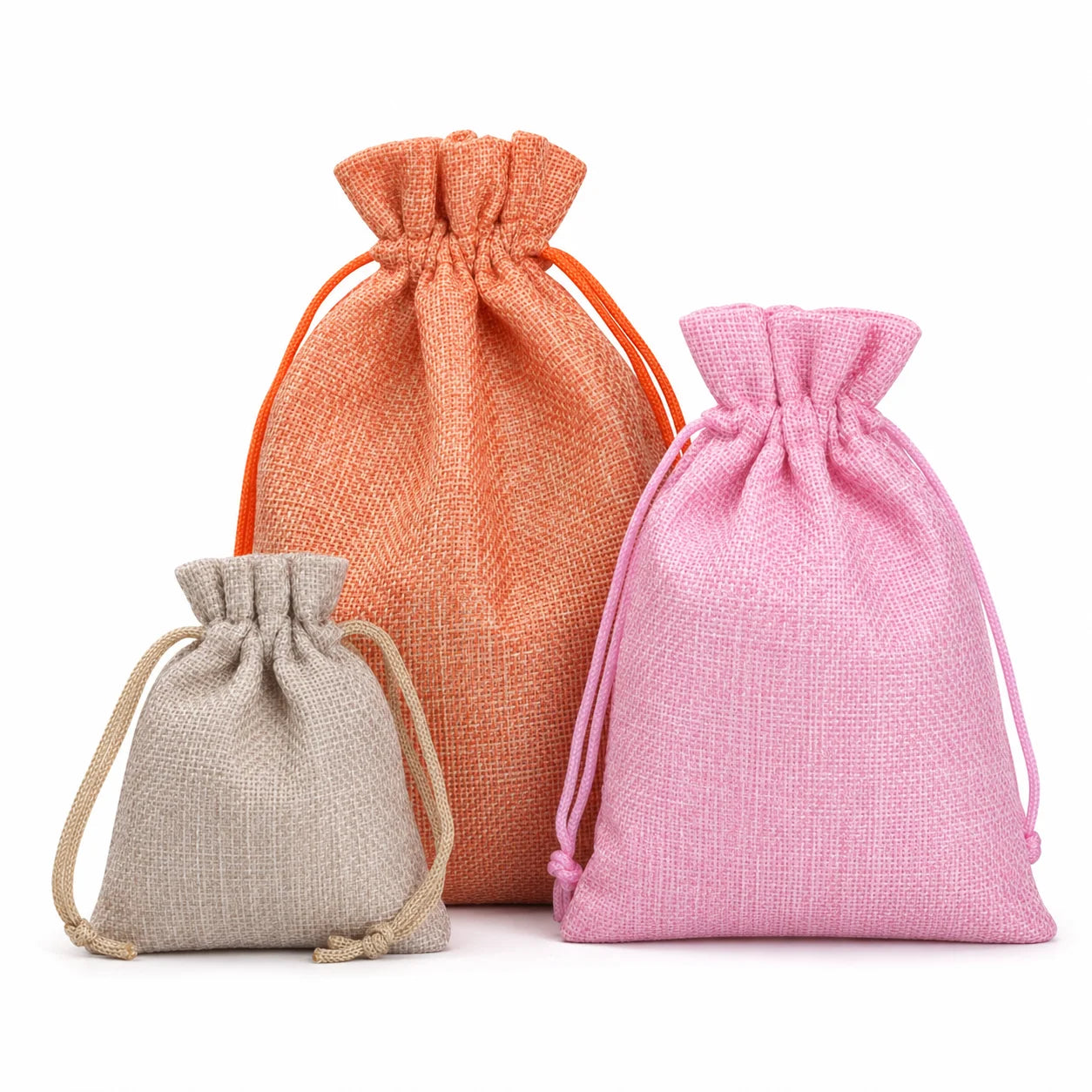 Three small drawstring pouches in different colors: a large peach-orange one, a medium pink one, and a small light beige one, arranged against a plain white background.