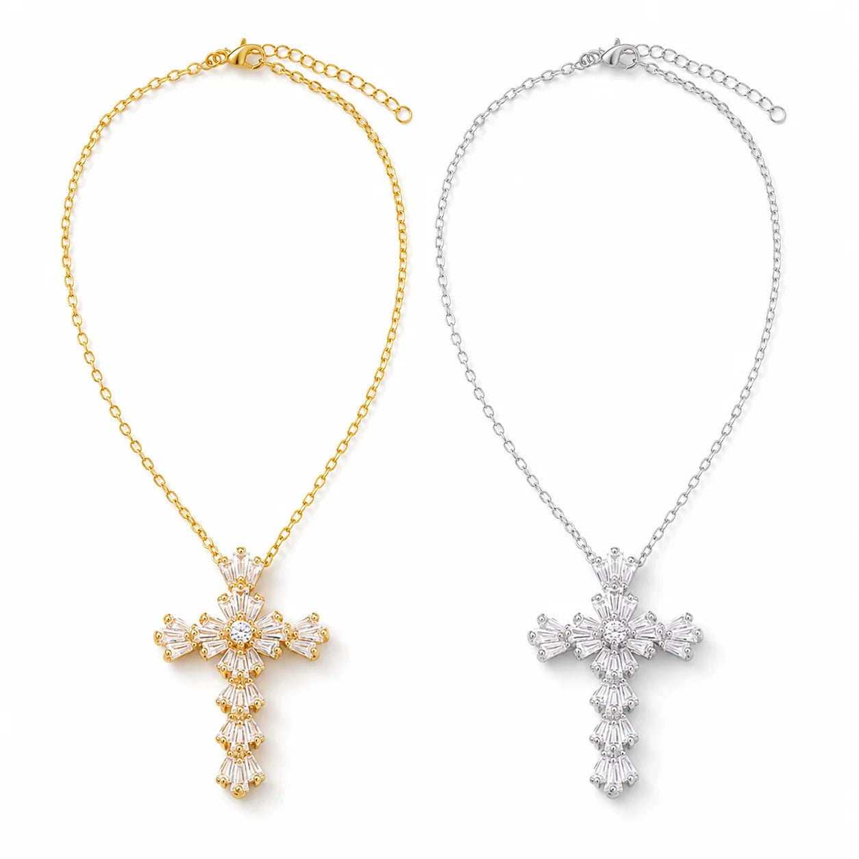 Two cross-shaped pendant necklaces on a plain white background, one in yellow gold and one in silver, each with clear faceted stones in a floral cluster design.