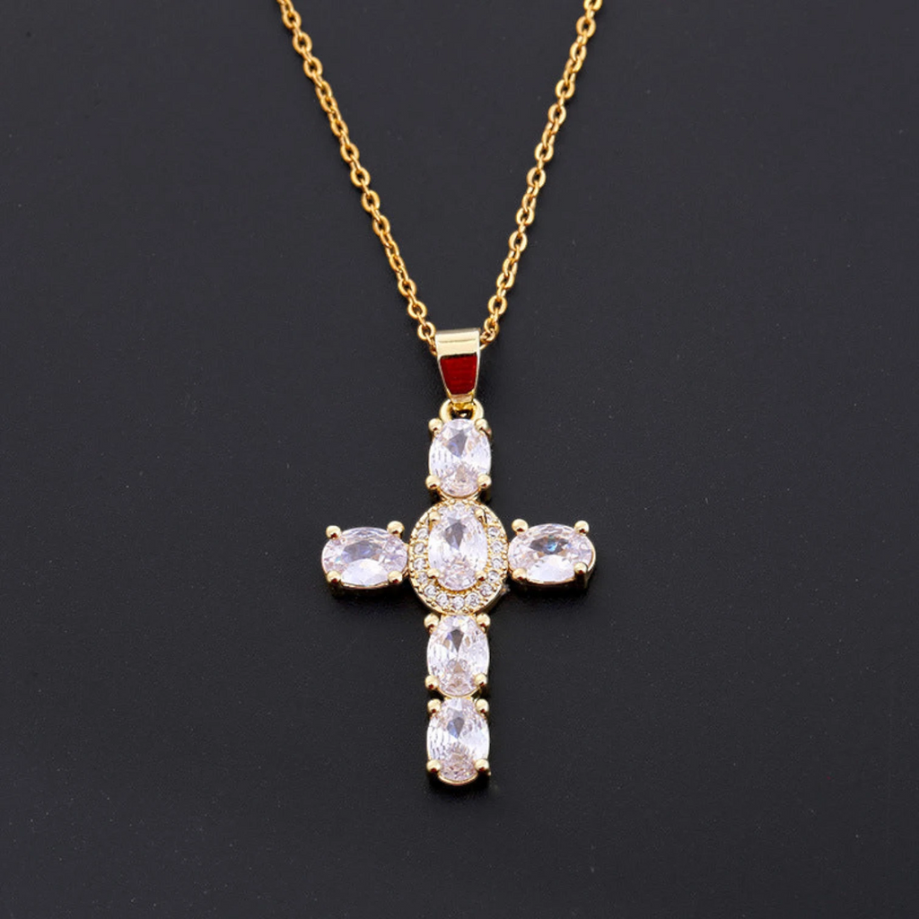 Gold cross pendant necklace with clear stones on a black background