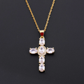 Gold cross pendant necklace with clear stones on a black background